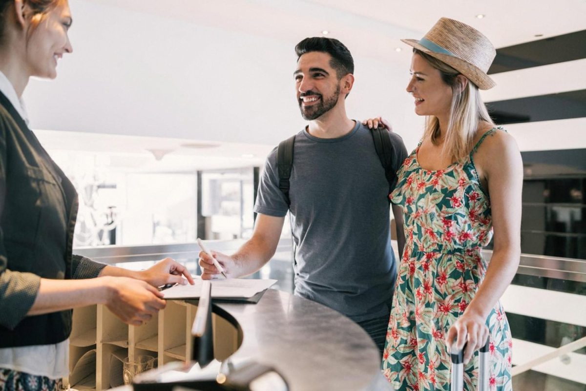 Hotel guests checking in at a modern front desk without paper registration cards