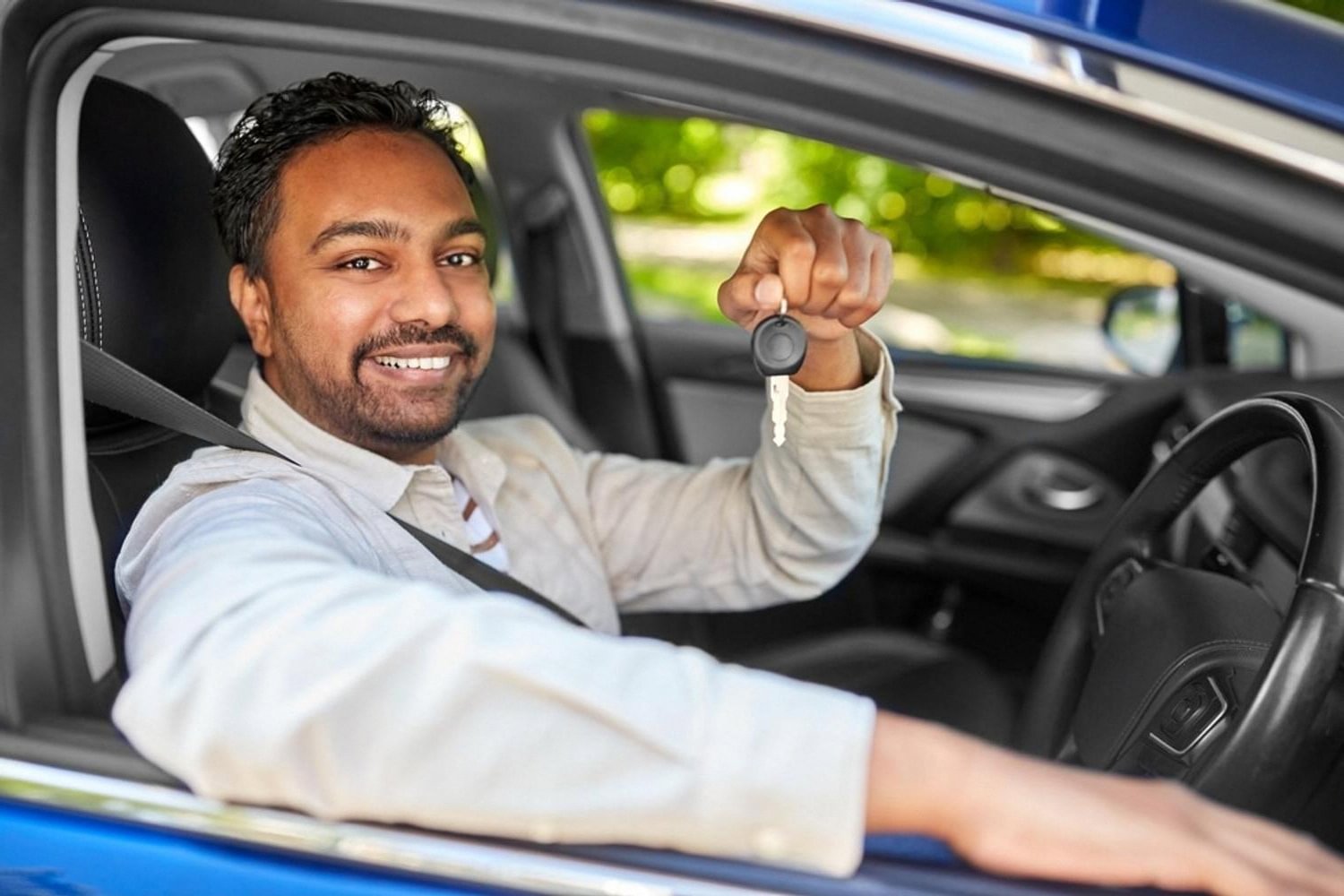 Smiling private driver in Dubai holding car keys after a monthly hire booking