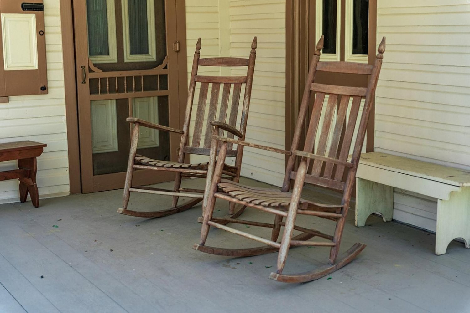 Two wooden rocking chairs available for individual rental on a covered porch